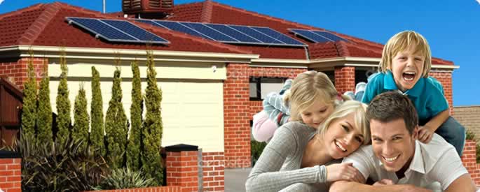 a family in front of their house with solar panels on the roof